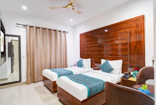a hotel room with two beds and a chair at Hotel Chanakya Inn in New Delhi
