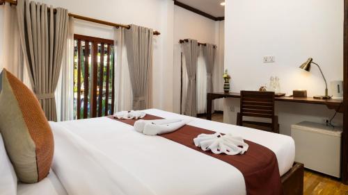 a bedroom with a white bed with towels on it at Khmer Lodge - Eco-Lodge in Phumĭ Réach Born