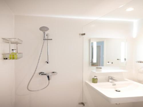 a white bathroom with a shower and a sink at Appartements nicht weit von der Donau in Linz