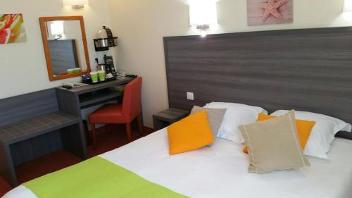 a bedroom with a bed with a desk and a mirror at Cit'Hotel Du Port Rhu in Douarnenez