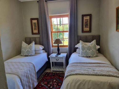 two twin beds in a room with a window at Barrydale Karoo - BOUTIQUE HOTEL in Barrydale