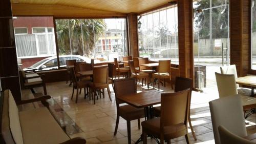 un restaurante con mesas, sillas y ventanas en Gelibolu Hotel, en Galípoli