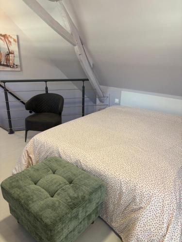 a bedroom with a bed with a green ottoman and a chair at Solesmes exceptionnel studio in Solesmes