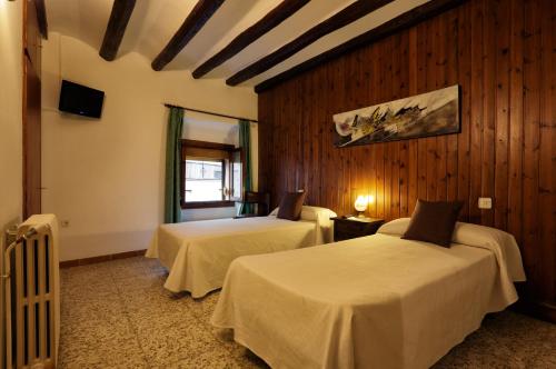 two beds in a room with wooden walls at Hostal i Apartaments Populetus in Poboleda