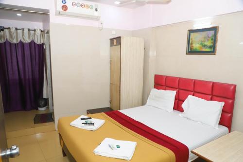 a bedroom with a bed with a red head board at Maharashtra Guest House in Kalyan