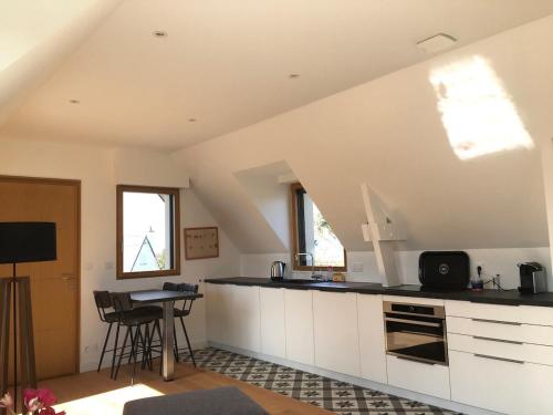 une cuisine mansardée avec des placards blancs et une table dans l'établissement APPARTEMENT NEUF 4 personnes A SAINT BRIAC SUR MER, à Saint-Briac-sur-Mer