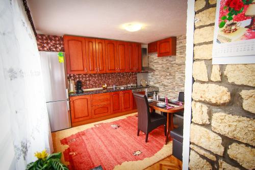 a kitchen with wooden cabinets and a table with chairs at Apartment Red House in Visoko