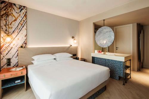 a bedroom with a large white bed and a desk at Hyatt Centric Malta in St. Julianʼs