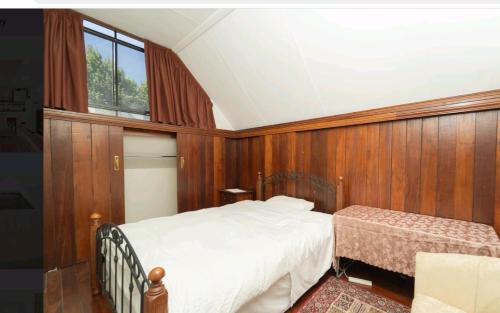 a bedroom with wood paneling and a bed and a window at Snow white's 2 bedroom dream Cottage with free parking in Perth