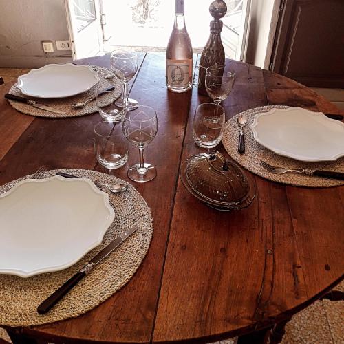 une table en bois avec des assiettes et des verres à vin dessus dans l'établissement La maison de Famille d'Uzès, à Aubussargues