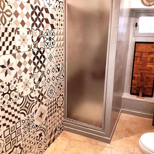 La salle de bains est pourvue d'une douche et d'un mur carrelé. dans l'établissement La maison de Famille d'Uzès, à Aubussargues