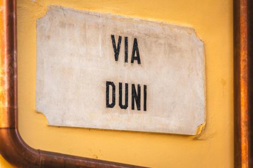 a sign that saysvia dunini on a yellow wall at Palazzo Canetti Locarno - Piazza Grande - Suites & Rooms - Easy Self Check-In in Locarno