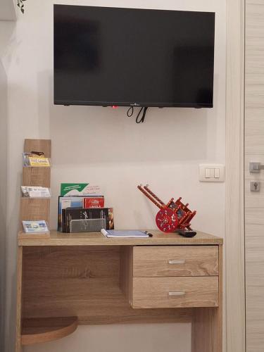 a television hanging on a wall above a wooden dresser at Casa Carruvedda in Avola