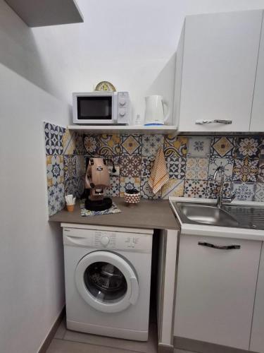 a kitchen with a washing machine and a microwave at Casa Carruvedda in Avola