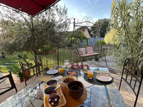 einen Tisch mit Essen auf der Terrasse in der Unterkunft Oasis de Détente avec Piscine et Jacuzzi 300m2 in Roézé-sur-Sarthe