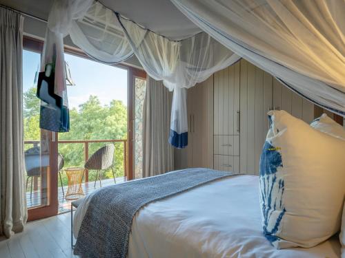 a bedroom with a bed and a large window at eKhaya Bush Lodge in Hoedspruit