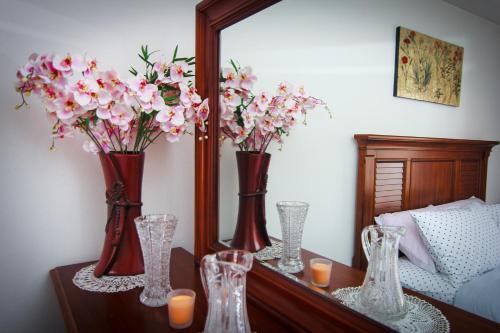 a group of vases with flowers on a table in front of a mirror at Apartment Red House in Visoko