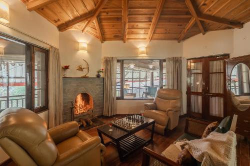 a living room with leather furniture and a fireplace at SaffronStays Casa Octavia in Bhīm Tāl