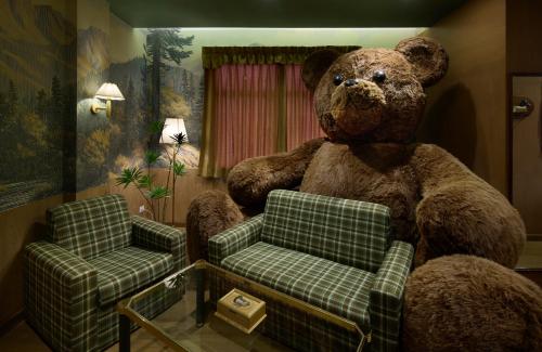 a large teddy bear sitting in a room with a chair at Kitsch Hotel in Bangkok