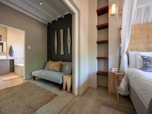 a bedroom with a bed and a chair in a room at eKhaya Bush Lodge in Hoedspruit