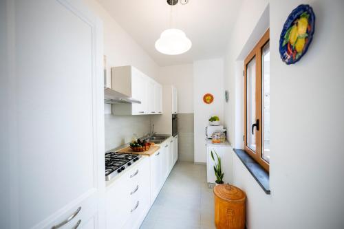 a white kitchen with white cabinets and a window at Villa Leonardo in the heart of Positano in Positano
