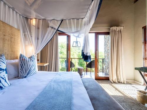 a bedroom with a large bed with a large window at eKhaya Bush Lodge in Hoedspruit