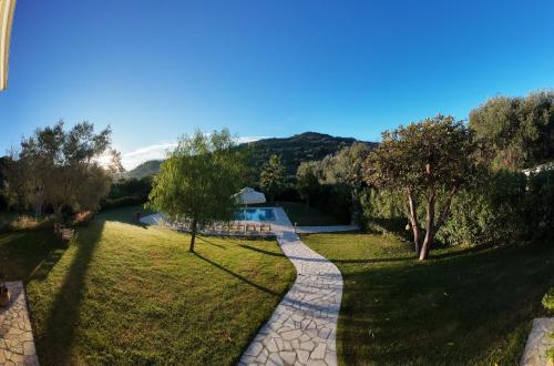 a walkway through a park with a swimming pool at Villa Stefania in Agios Georgios Pagon
