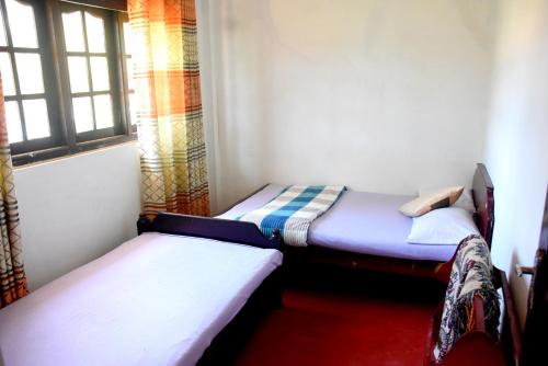 two twin beds in a room with a window at The Dew Drop View in Nuwara Eliya