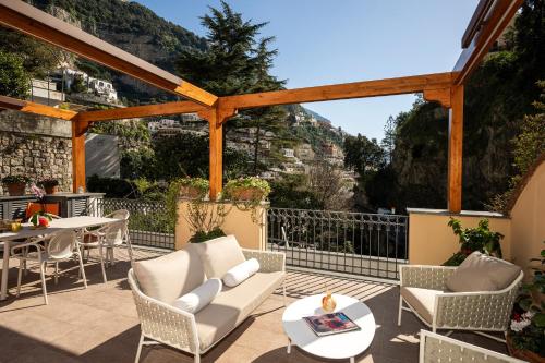 a patio with chairs and tables and a view of the mountains at Villa Leonardo in the heart of Positano in Positano