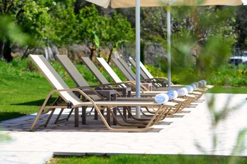a row of lounge chairs with an umbrella at Villa Stefania in Agios Georgios Pagon