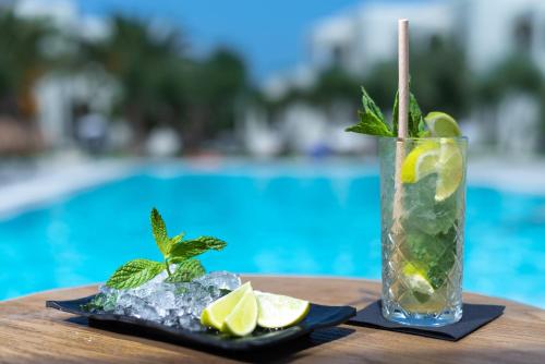 a drink on a table next to a pool at Malena Hotel & Suites - Adults Only by Omilos Hotels in Amoudara Herakliou