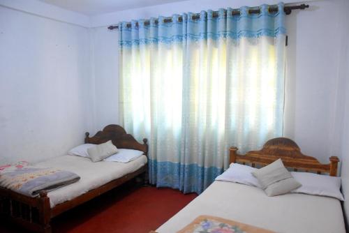 two twin beds in a room with a window at The Dew Drop View in Nuwara Eliya