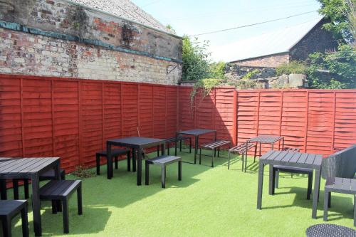 a group of tables and benches in front of a red fence at The Kirkcudbright Bay Hotel in Kirkcudbright