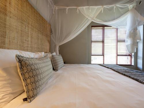 a bedroom with a large white bed with a window at eKhaya Bush Lodge in Hoedspruit