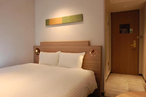a bedroom with a large white bed and a door at Izumo Royal Hotel in Izumo