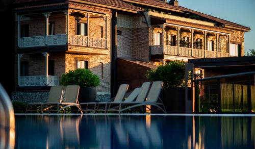 a group of chairs sitting on the edge of a swimming pool at Chateau Mephis Kalaki in Akhalkʼalakʼi