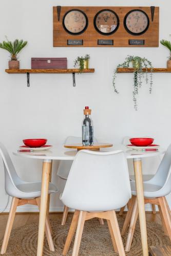 une table à manger avec des chaises blanches et des horloges murales dans l'établissement Transports, parking, A/C & equipped for long stays, à Saint-Ouen