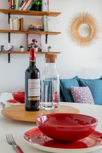 - une bouteille de vin assise sur une table avec des bols rouges dans l'établissement Transports, parking, A/C & equipped for long stays, à Saint-Ouen