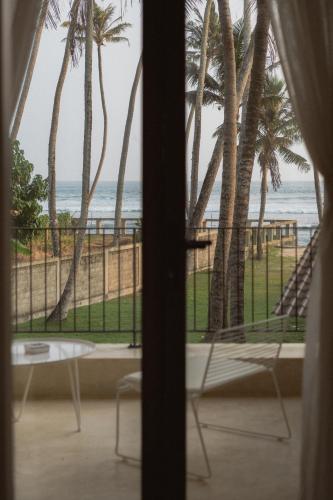 a room with a view of the beach from a window at Harding Boutique Hotel in Ahangama
