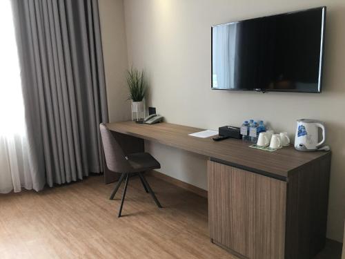 a desk in a hotel room with a television on the wall at The Luxe Da Lat in Da Lat