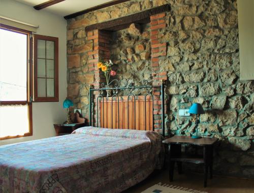 a bedroom with a stone wall with a bed and a table at Apartamentos Maite in Oreña