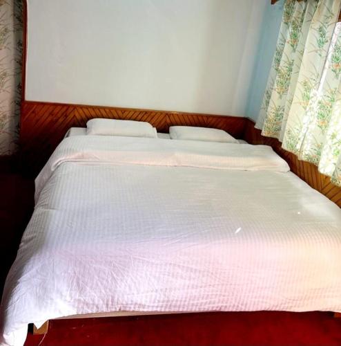 a large white bed with two pillows on it at Kamal Homestay in Nainital