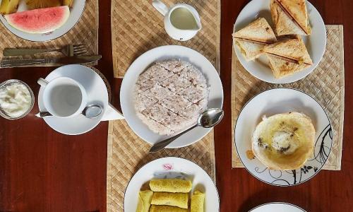 a table with plates of food and cups of coffee at Happy Man Village in Bentota