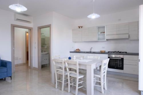 a white kitchen with a white table and chairs at Guest House in Mercatello