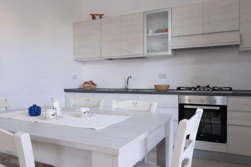 a white kitchen with a white table and chairs at Guest House in Mercatello