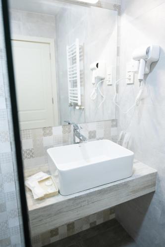 a white bathroom with a sink and a mirror at Astana Palace in Gori
