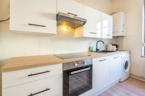 une cuisine avec des armoires blanches, un évier et un lave-vaisselle dans l'établissement Magnifique appartement 6Pers Stationnement Gratuit Centre 1, à Mulhouse