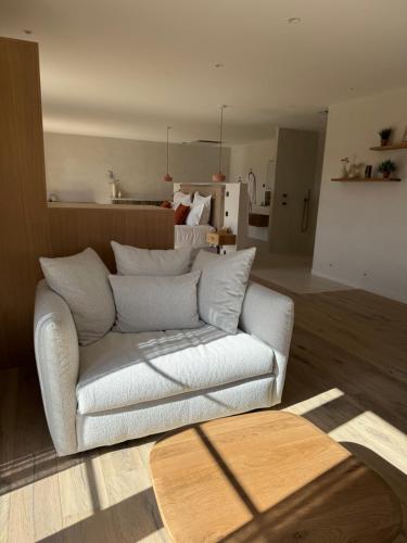 a living room with a white couch and a kitchen at Ferme La Clavière, Suite de Luxe Lou Estello in Mane