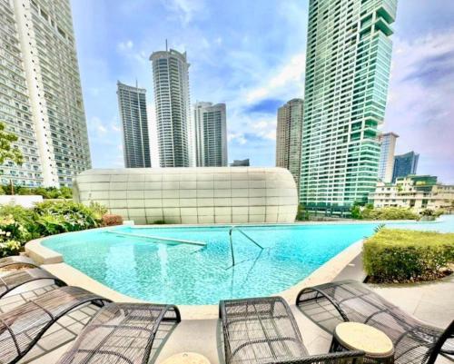 a large swimming pool in a city with tall buildings at Luxury California King Suite with Pool and City View in Manila