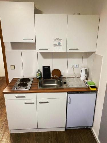 a small kitchen with white cabinets and a sink at Landhaus Herdt in Lauda-Königshofen